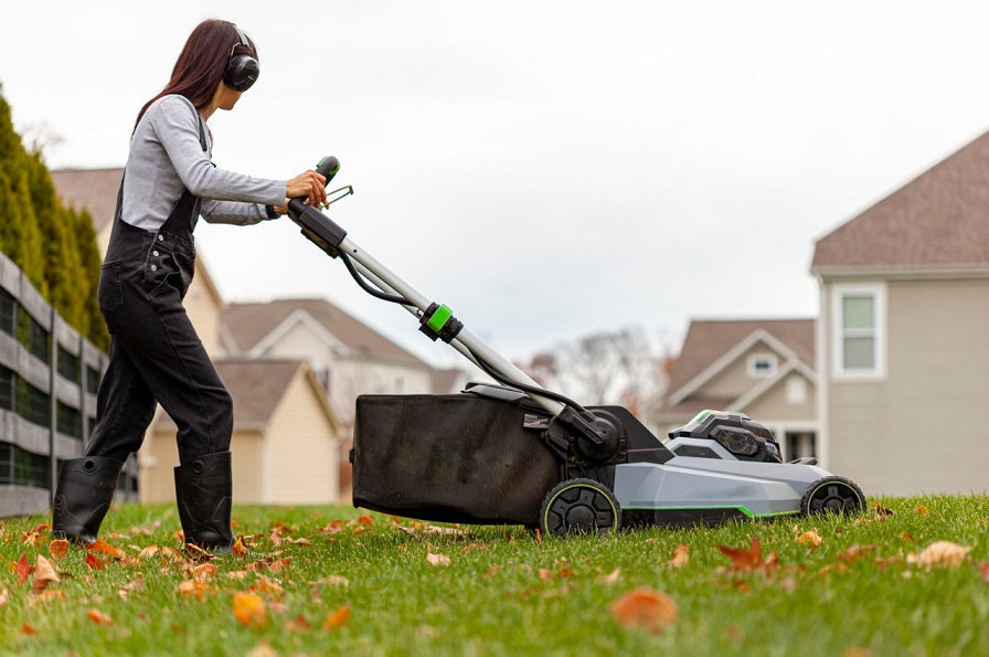 Woman mowing lawn near house, Segway Navimow robot series visible.