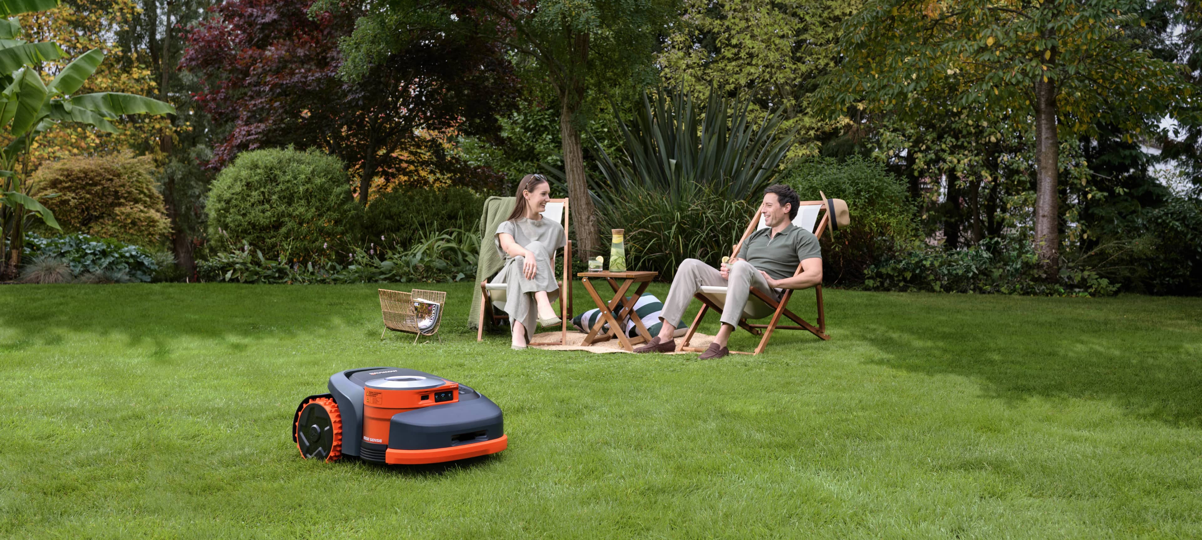 Navimow i105E robot lawn mower mows while a couple relaxes.