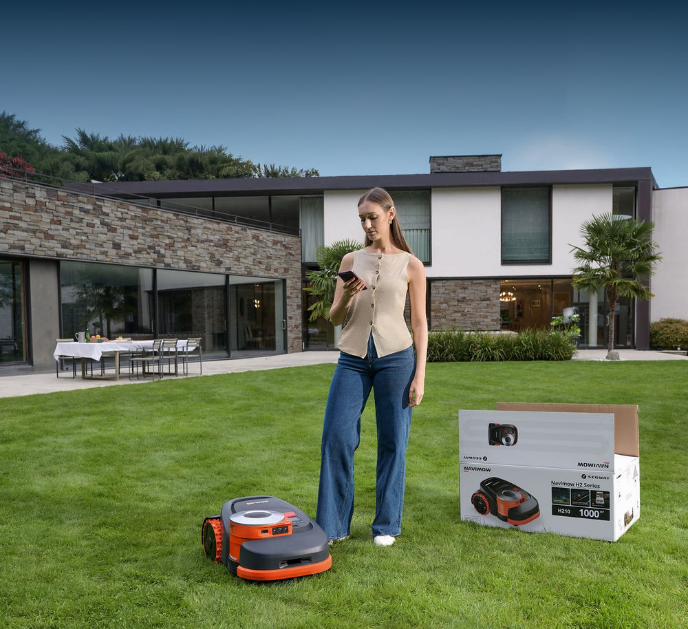 Segway Navimow H210 robot lawn mower with woman on grass.