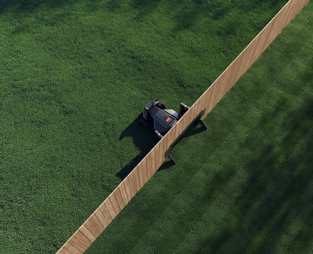 Navimow i110N robot lawn mower moves through a wooden fence.