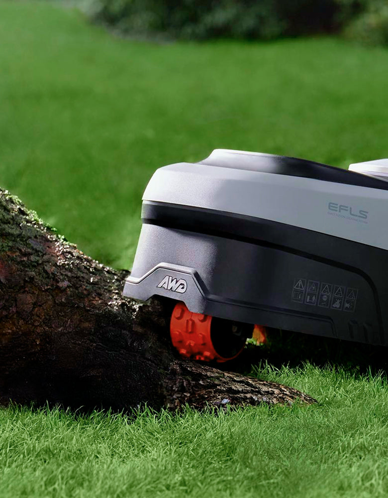 Close-up of the Navimow i2 AWD rear wheel beside a tree root
